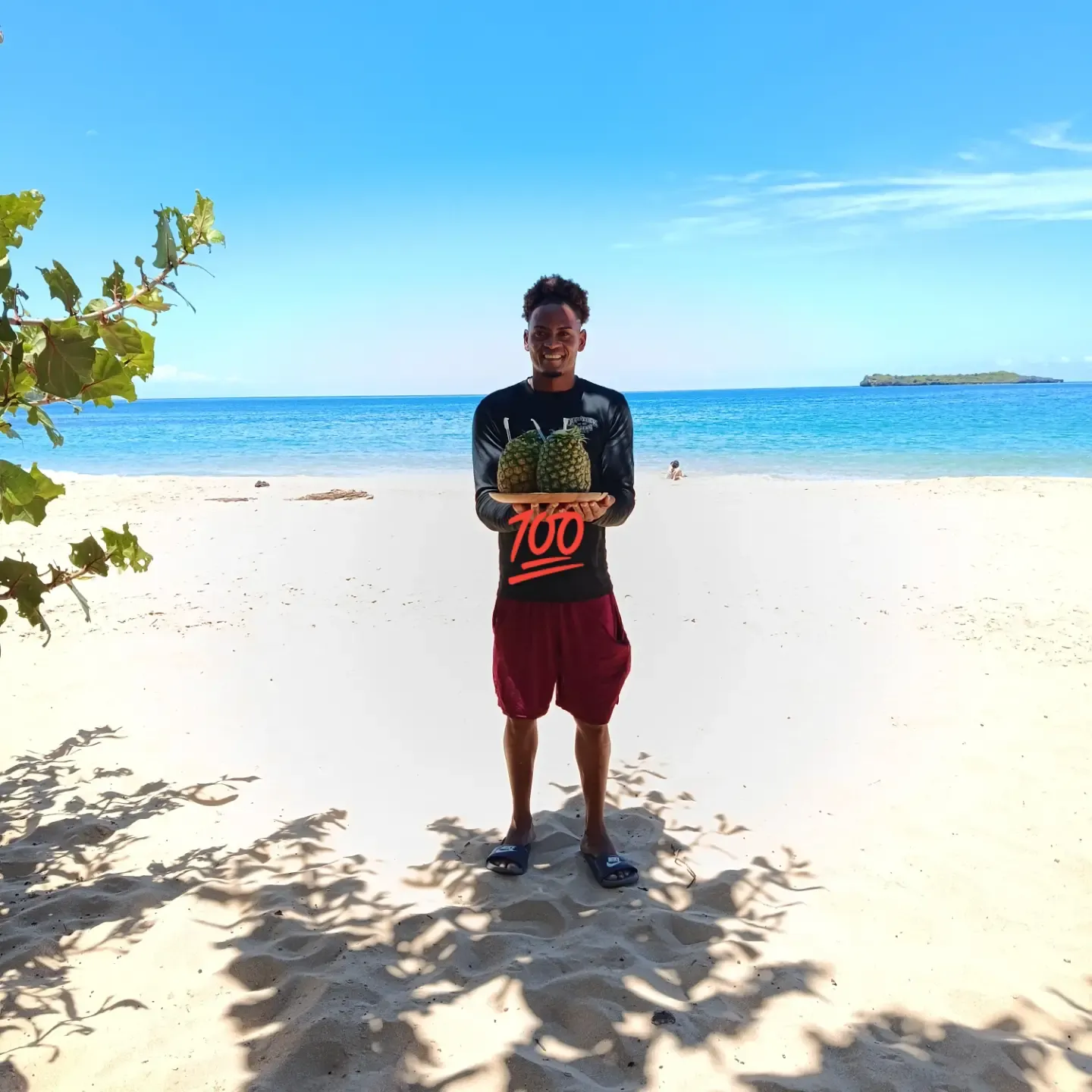 Emiliano on the beach holding two pineapples